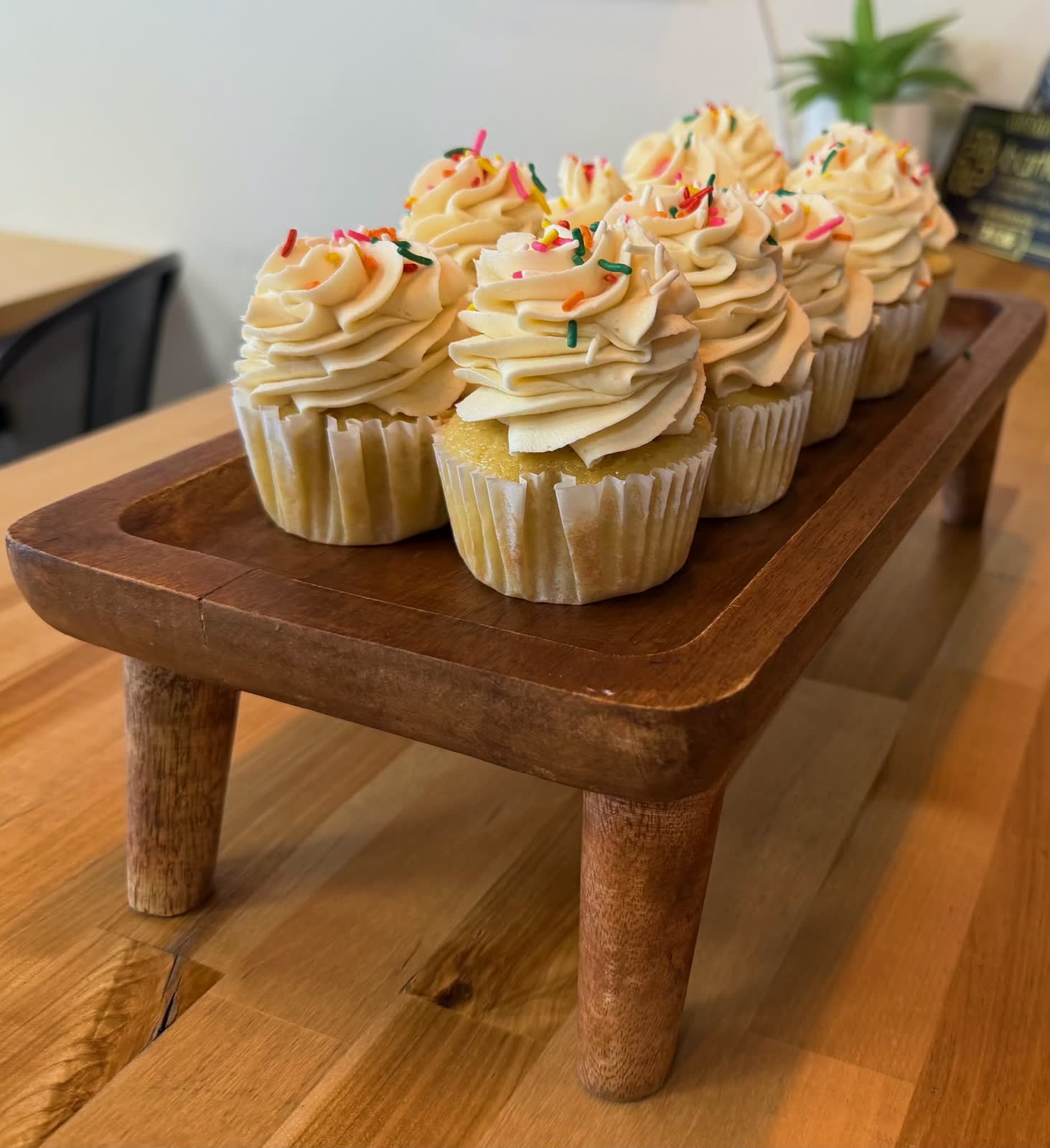 Vanilla cupcakes with sprinkles on a wooden stand