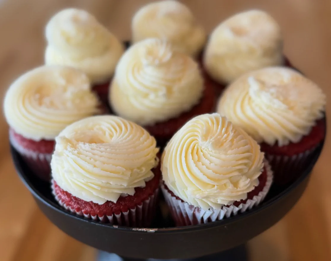 Red velvet cupcakes with cream cheese frosting on a cake stand